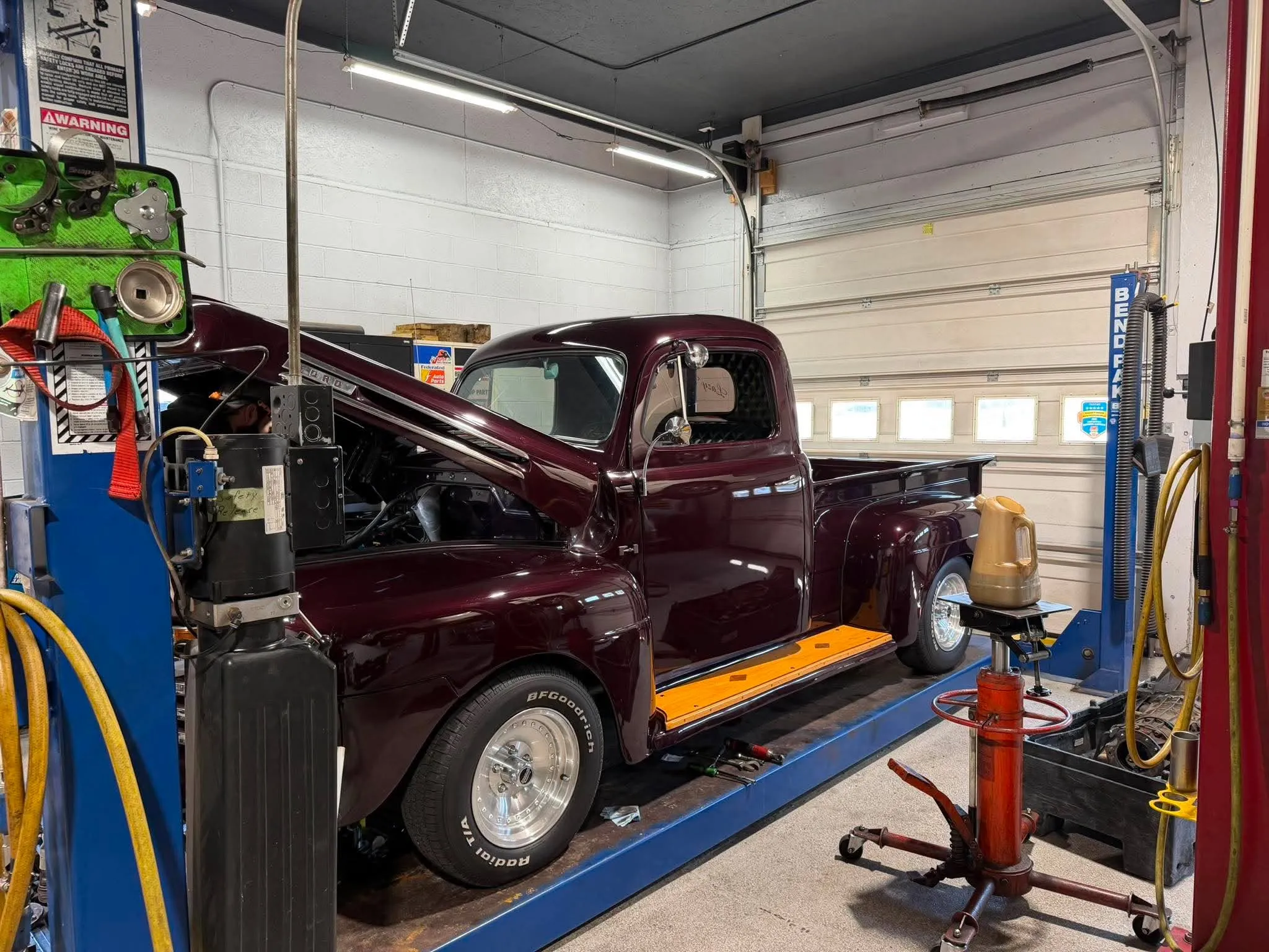 Classic Maroon Ford Truck — Maroon classic Ford F-100 pickup truck raised on a drive-on lift for service.